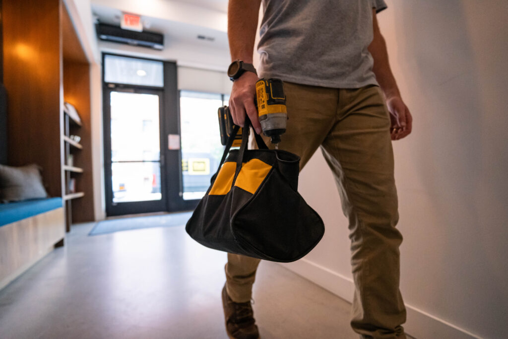 Service Tech with tool bag walking in commercial building.